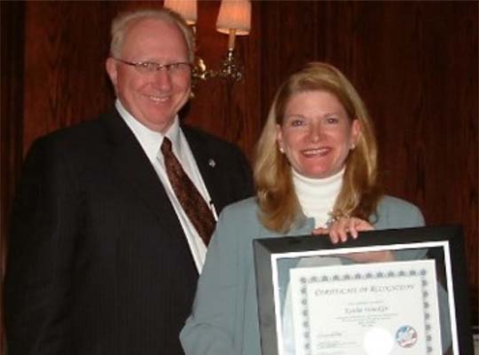 The Commission’s first Executive Director, Don Blackburn, presents a recognition award to the first Rules Committee Chair, Kathie Winckler (TX). (2005)