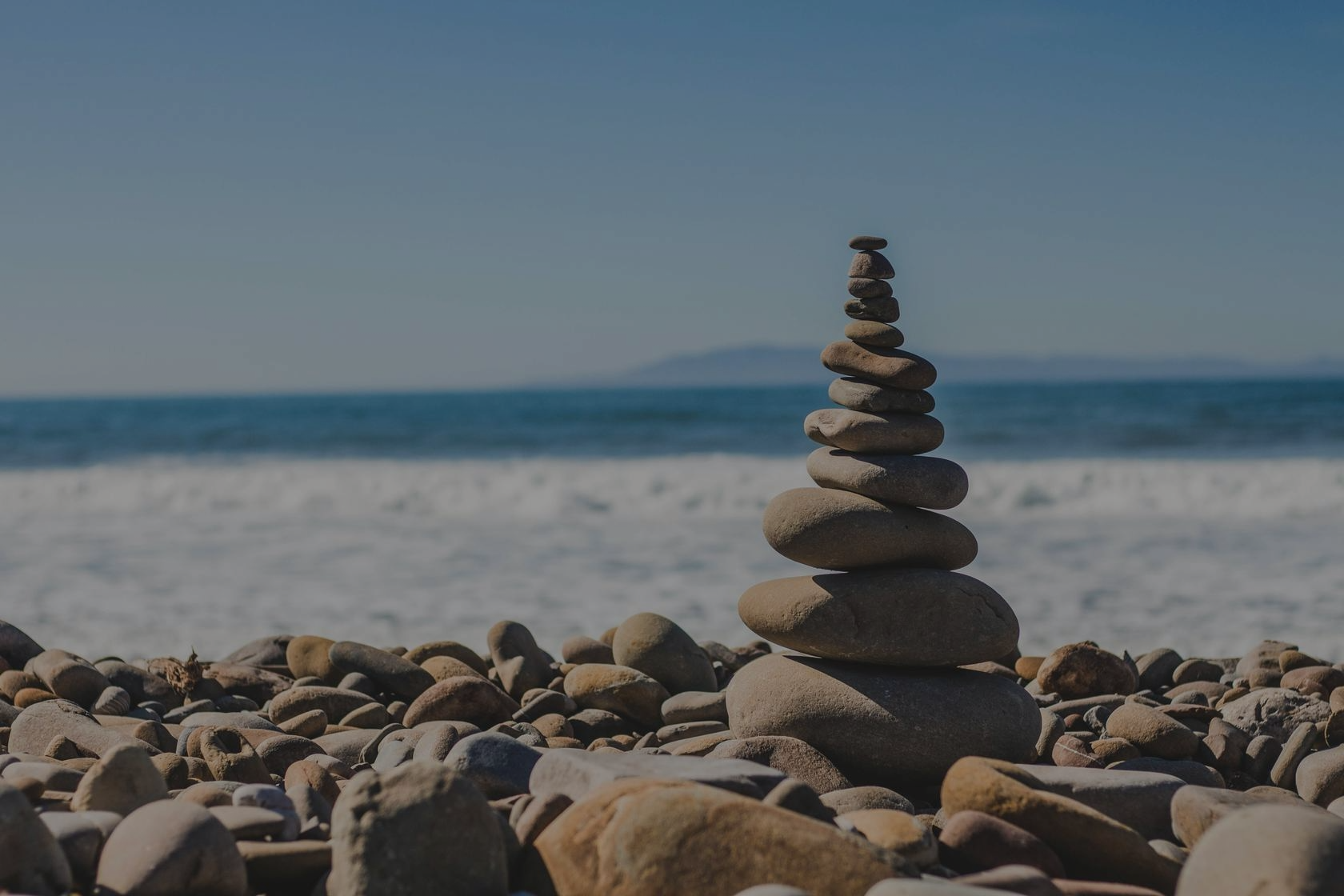 Stacked rocks on a beach with overlay